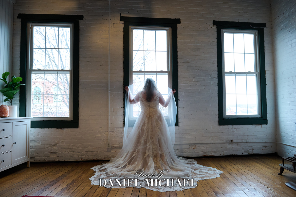 Woman in wedding dress standing at window